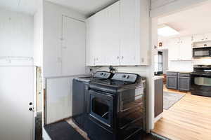 Washroom with washer and clothes dryer, cabinets, and light hardwood / wood-style flooring