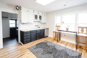 Kitchen with dishwasher, light hardwood / wood-style floors, white cabinetry, and sink