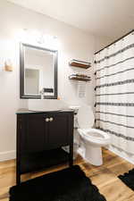 Bathroom featuring walk in shower, hardwood / wood-style floors, a textured ceiling, toilet, and vanity