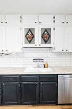 Kitchen with tasteful backsplash, stainless steel dishwasher, white cabinetry, and sink