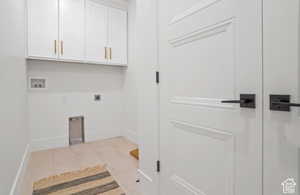 Washroom featuring electric dryer hookup, washer hookup, light tile patterned floors, and cabinets