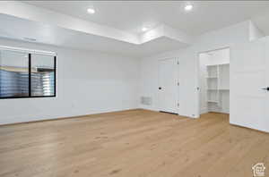 Unfurnished bedroom featuring a walk in closet and light wood-type flooring