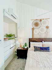 Carpeted bedroom with a wall unit AC and wooden walls