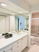 Full bathroom featuring tile patterned floors, vanity, toilet, and enclosed tub / shower combo