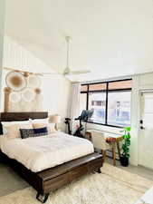 Carpeted bedroom with ceiling fan, a textured ceiling, and wooden walls