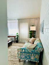 Living area with carpet flooring, baseboard heating, and a textured ceiling