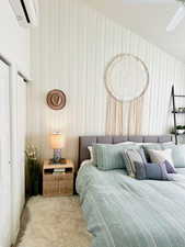 Bedroom with wood walls, ceiling fan, a textured ceiling, light colored carpet, and a wall unit AC