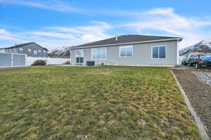 Rear view of house with a mountain view, a yard, and central AC unit