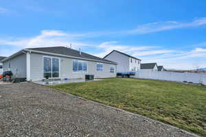 Back of property with cooling unit, a yard, and a patio