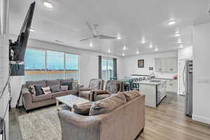 Living room featuring ceiling fan, light wood-type flooring, and a textured ceiling