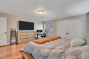 Bedroom featuring a textured ceiling, light hardwood / wood-style flooring, and a closet