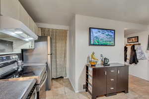 Kitchen featuring white cabinets, dark brown cabinets, stainless steel electric range oven, and range hood