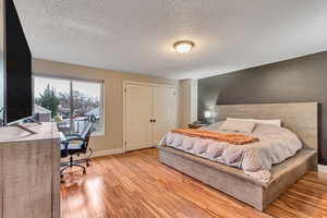 Bedroom with a textured ceiling, light wood-type flooring, and a closet