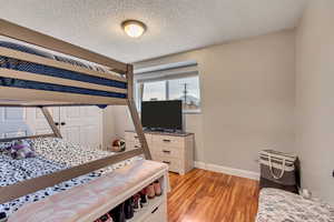 Bedroom with a textured ceiling and light hardwood / wood-style flooring