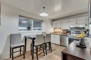 Kitchen featuring white cabinetry, sink, hanging light fixtures, light tile patterned flooring, and appliances with stainless steel finishes