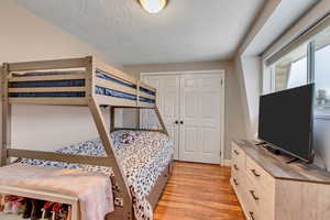 Bedroom featuring light wood-type flooring, a textured ceiling, and a closet