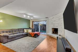 Living room featuring a fireplace, light hardwood / wood-style floors, and a textured ceiling