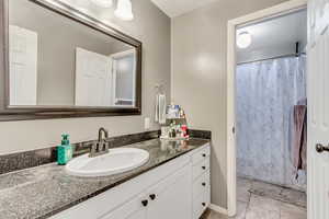 Bathroom with tile patterned floors, a shower with curtain, and vanity