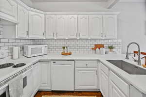 Kitchen featuring white cabinetry, white appliances, and sink