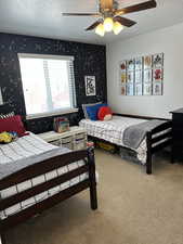 Bedroom with ceiling fan, a textured ceiling, and carpet flooring