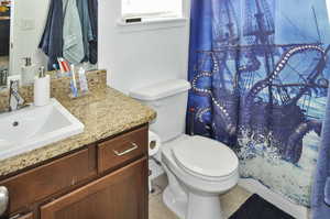 Bathroom featuring tile patterned flooring, vanity, toilet, and curtained shower