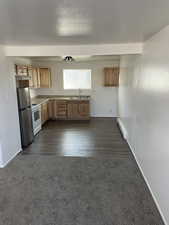 Kitchen featuring stainless steel fridge, dark carpet, a baseboard heating unit, sink, and white electric range