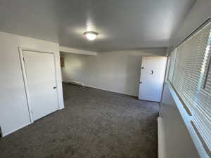 Carpeted spare room with baseboard heating and a textured ceiling