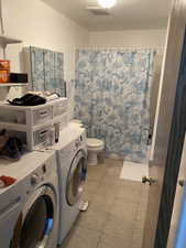 Clothes washing area featuring washing machine and dryer and light tile patterned floors