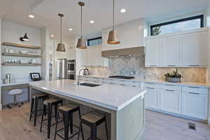 Kitchen with white cabinets, decorative light fixtures, and sink