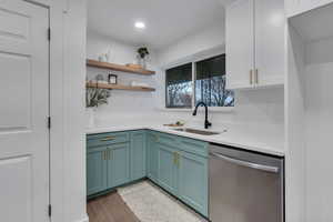 Kitchen with white cabinetry, dishwasher, light hardwood / wood-style flooring, and sink