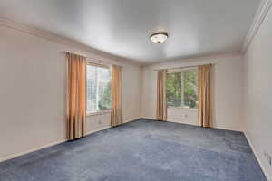 Unfurnished room with dark colored carpet and crown molding