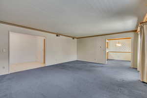 Carpeted empty room with ornamental molding and an inviting chandelier