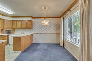 Kitchen with dishwasher, an inviting chandelier, kitchen peninsula, decorative light fixtures, and ornamental molding