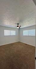 Carpeted spare room featuring a textured ceiling and ceiling fan