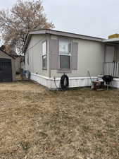 View of property exterior featuring a lawn and a storage shed