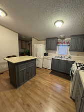 Kitchen featuring white appliances, light hardwood / wood-style floors, gray cabinetry, and sink