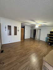 Unfurnished living room with a textured ceiling, hardwood / wood-style flooring, and ceiling fan