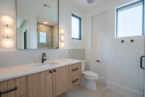 Bathroom with tile patterned floors, vanity, toilet, and a shower with door