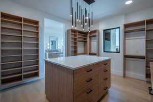 Walk in closet featuring a notable chandelier and light wood-type flooring