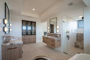 Bathroom with vanity, a tray ceiling, and a shower with shower door