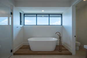 Bathroom with hardwood / wood-style floors, toilet, and a tub