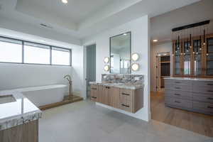 Bathroom with a bathing tub, vanity, and a raised ceiling