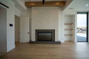 Unfurnished living room with beam ceiling, built in features, and light wood-type flooring