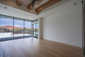 Unfurnished room with ceiling fan, beam ceiling, a barn door, a wall of windows, and a mountain view