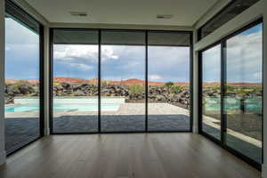 Doorway to outside featuring a mountain view, hardwood / wood-style floors, expansive windows, and a healthy amount of sunlight