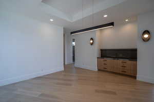 Unfurnished living room featuring a tray ceiling and light hardwood / wood-style flooring