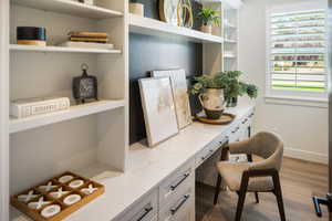 Office area with built in desk and light wood-type flooring