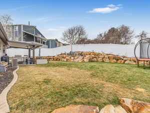 View of yard with a trampoline and central AC