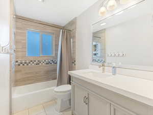 Full bathroom featuring toilet, shower / bath combo with shower curtain, vanity, and tile patterned flooring