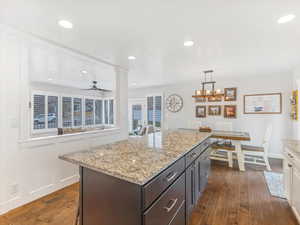 Kitchen featuring dark brown cabinetry, decorative light fixtures, dark hardwood / wood-style floors, and ceiling fan with notable chandelier